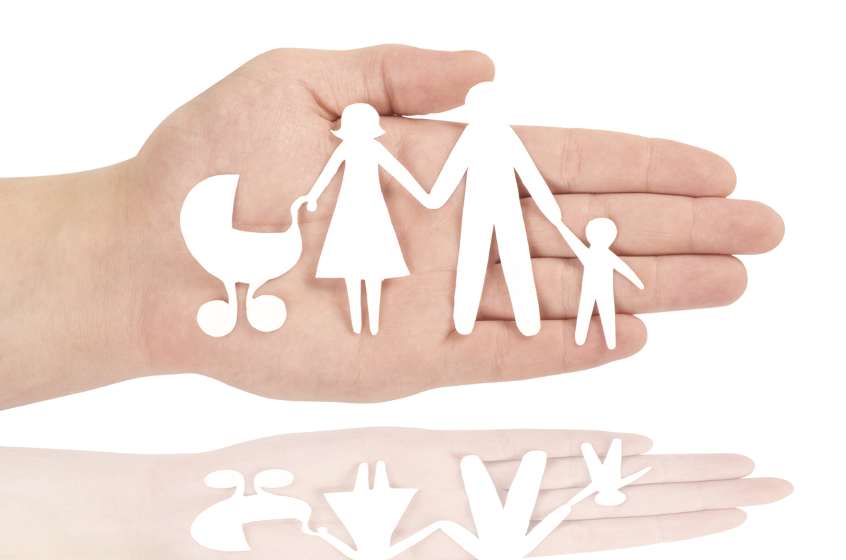 Paper cutout of a family in the palm of a hand.