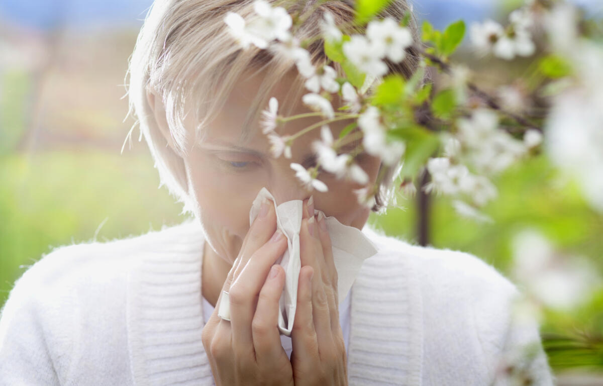 Woman blowing nose during allergy season.