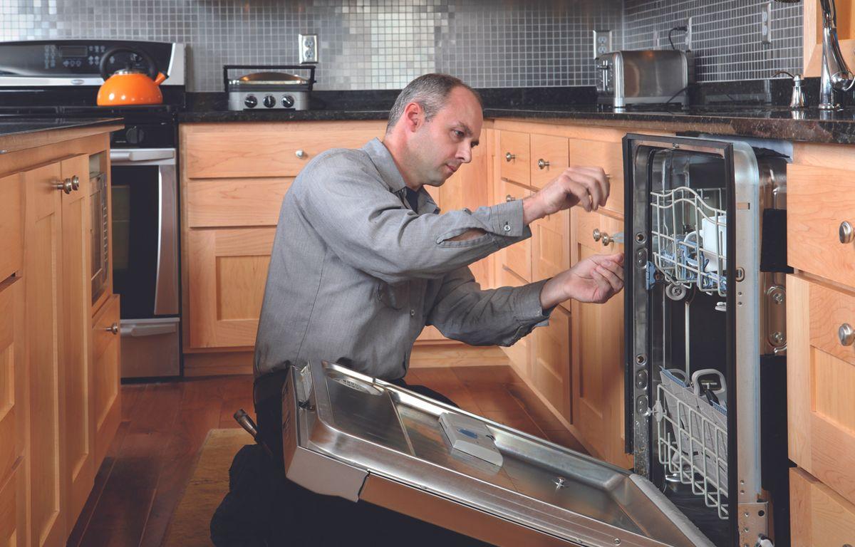 Appliance service technician fixes dishwasher