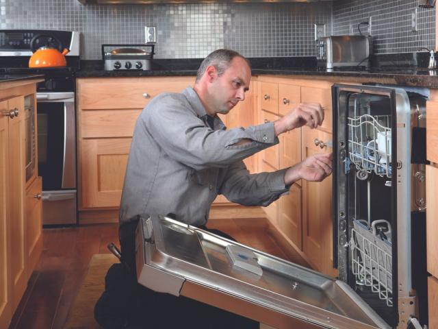 Appliance service technician fixes dishwasher