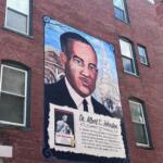 Mural on a brick wall showing a large portrait of Dr. Albert C. Johnston with a commemorative text panel beneath it