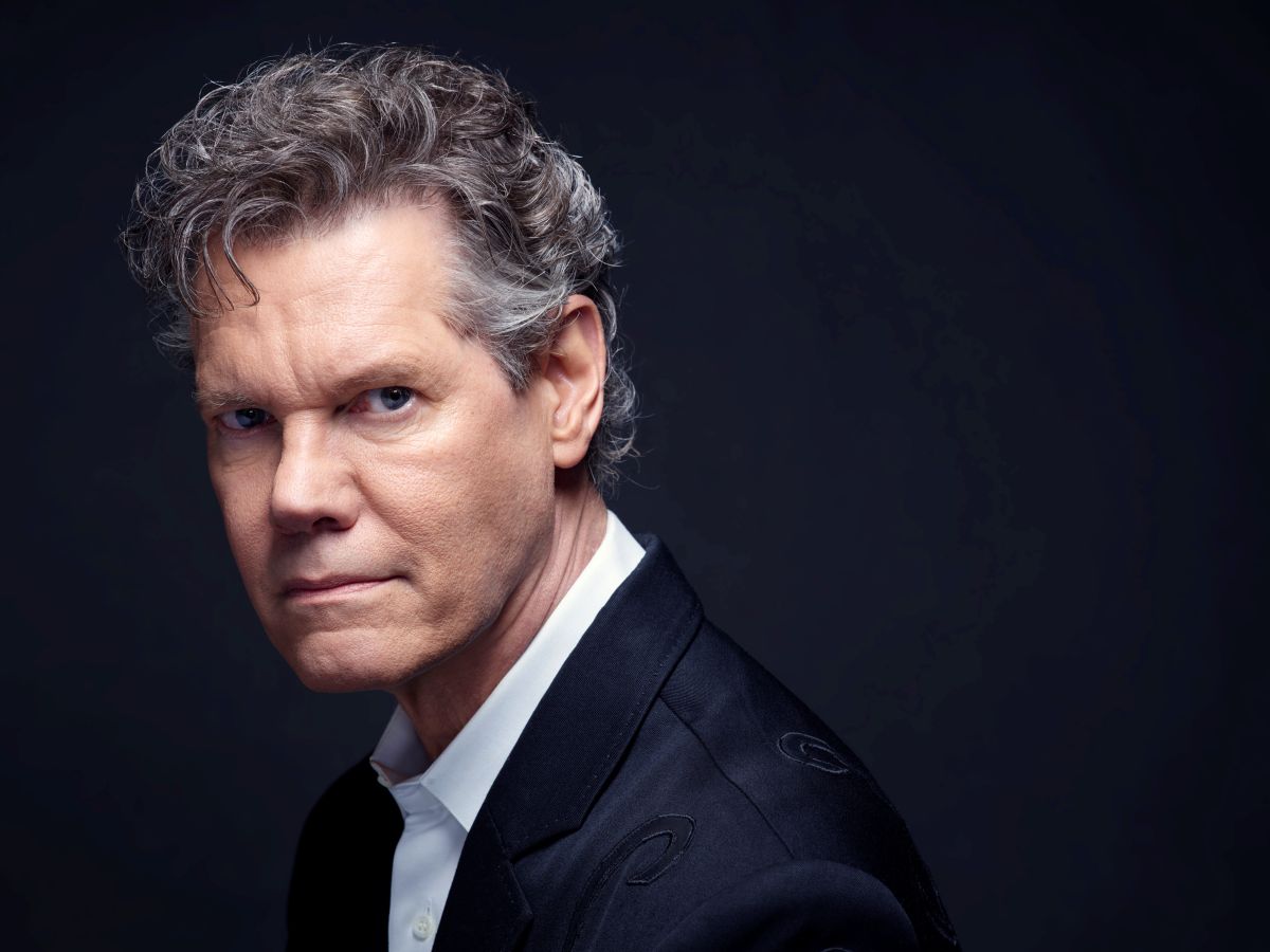 Portrait of a middle-aged man with gray hair in a dark suit against a dark background, looking at the camera.