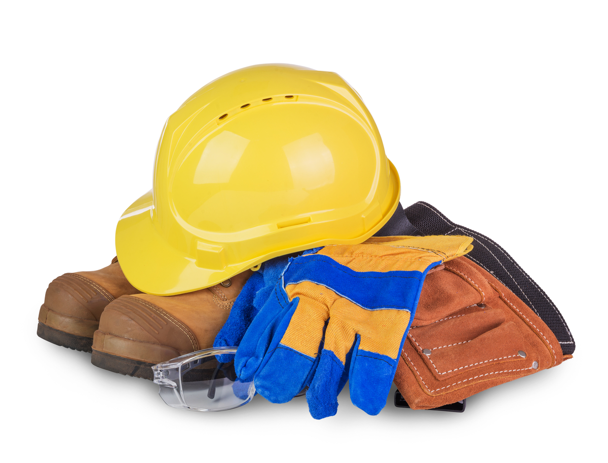 Yellow hard hat atop brown work boots with blue and yellow gloves, safety glasses, and a brown tool pouch stacked together.