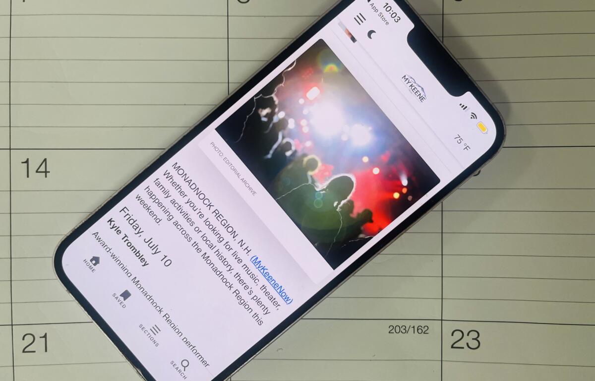 Smartphone tilted on a calendar page, displaying a colorful article image and text.
