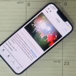 Smartphone tilted on a calendar page, displaying a colorful article image and text.