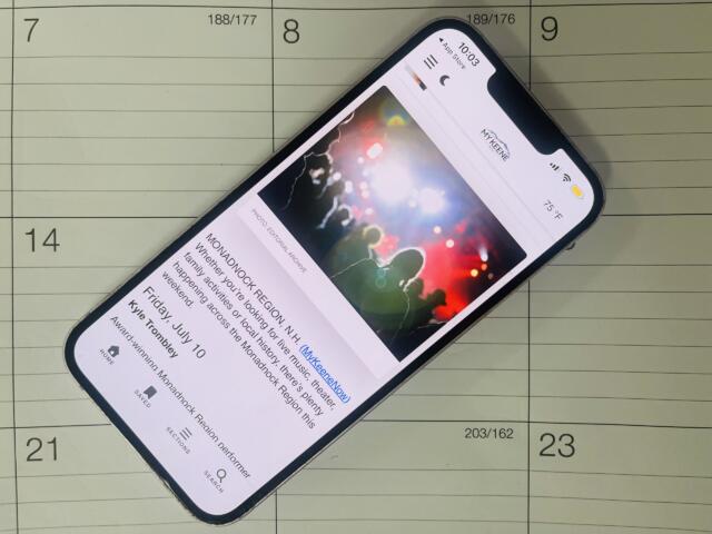 Smartphone tilted on a calendar page, displaying a colorful article image and text.